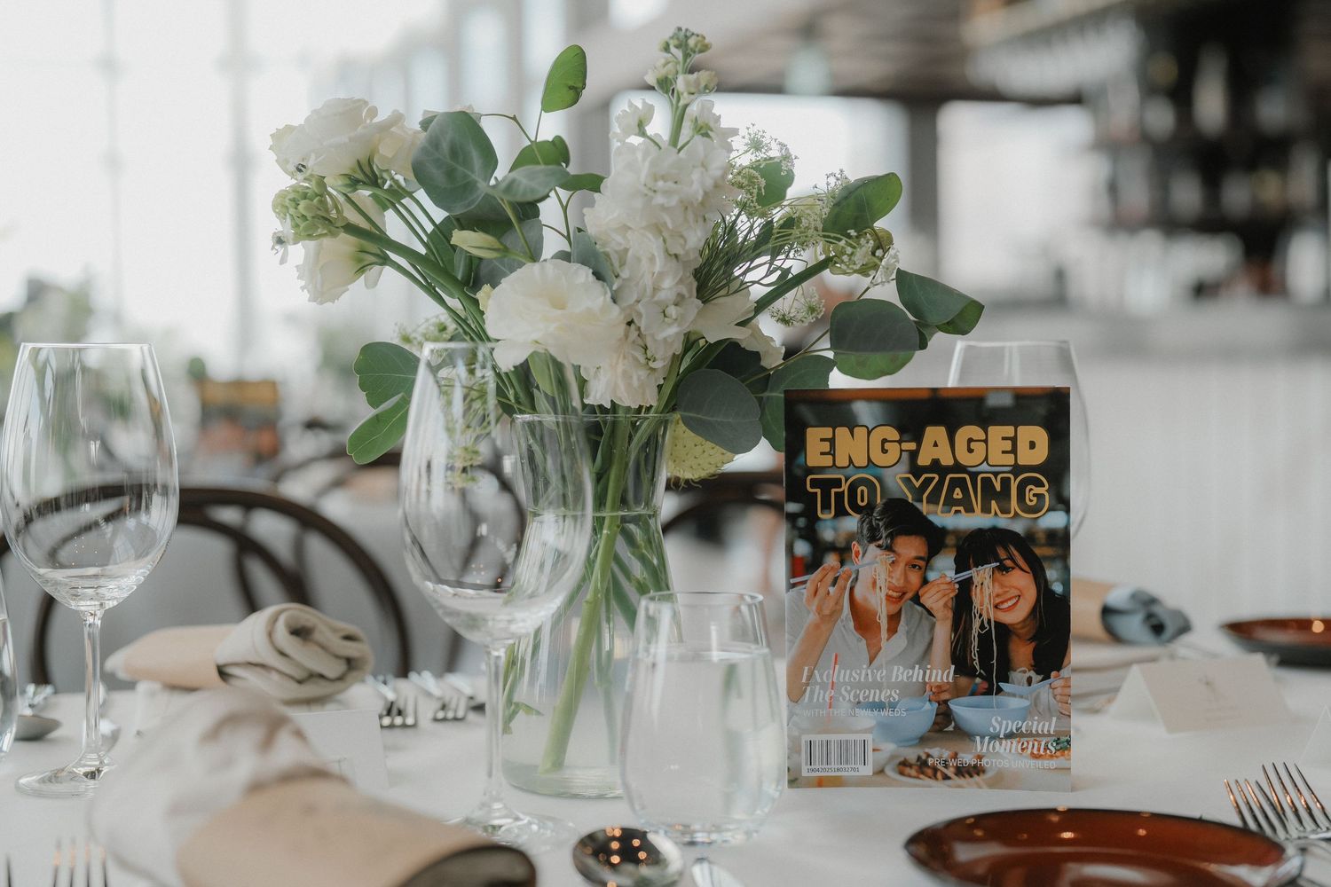 White and green wedding table decorations featuring eucalyptus leaves and simple floral centerpieces.