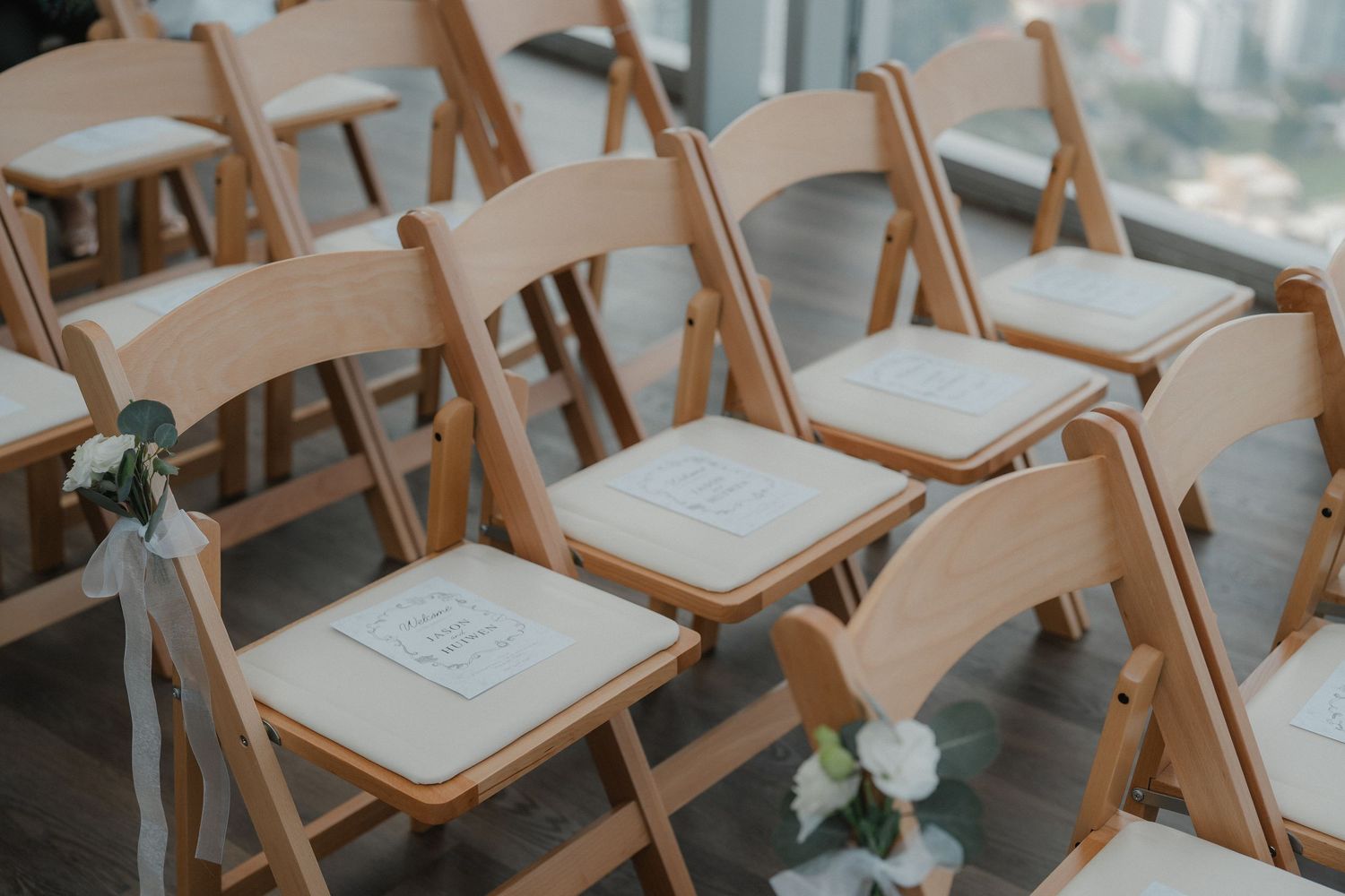 Row of empty wooden folding chairs arranged for wedding ceremony with floral decor.