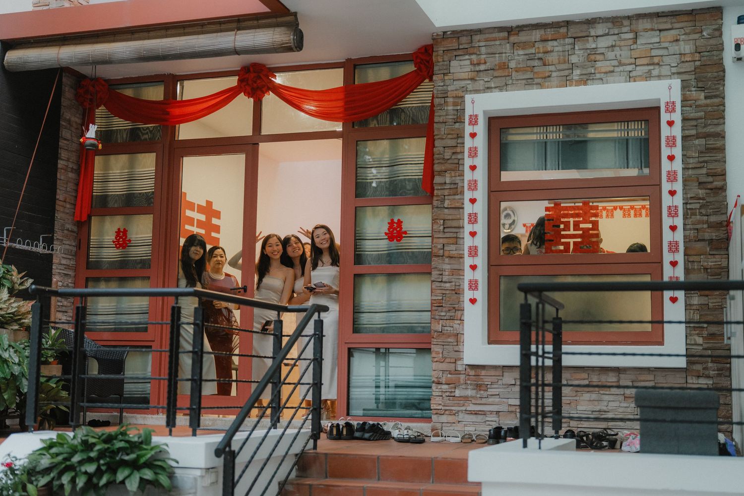 Large red decorative bow adorns the entrance of a modern building with glass windows and stone accents.