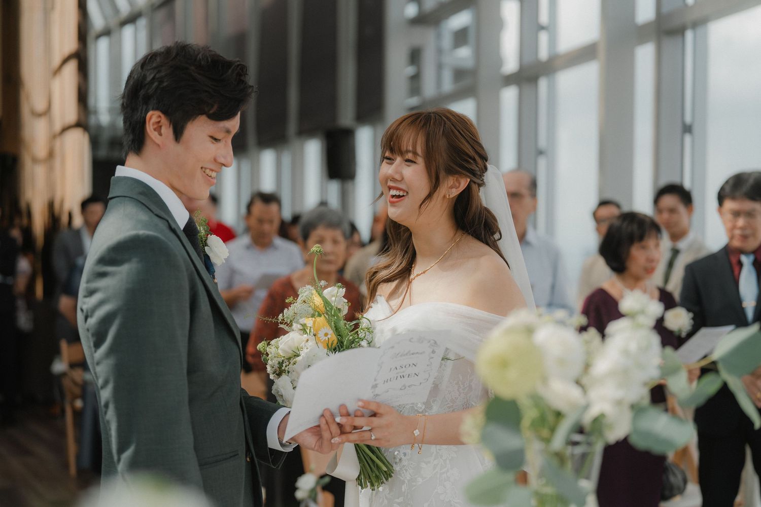 Couple exchanges vows during elegantly decorated indoor wedding ceremony with floral arrangements.