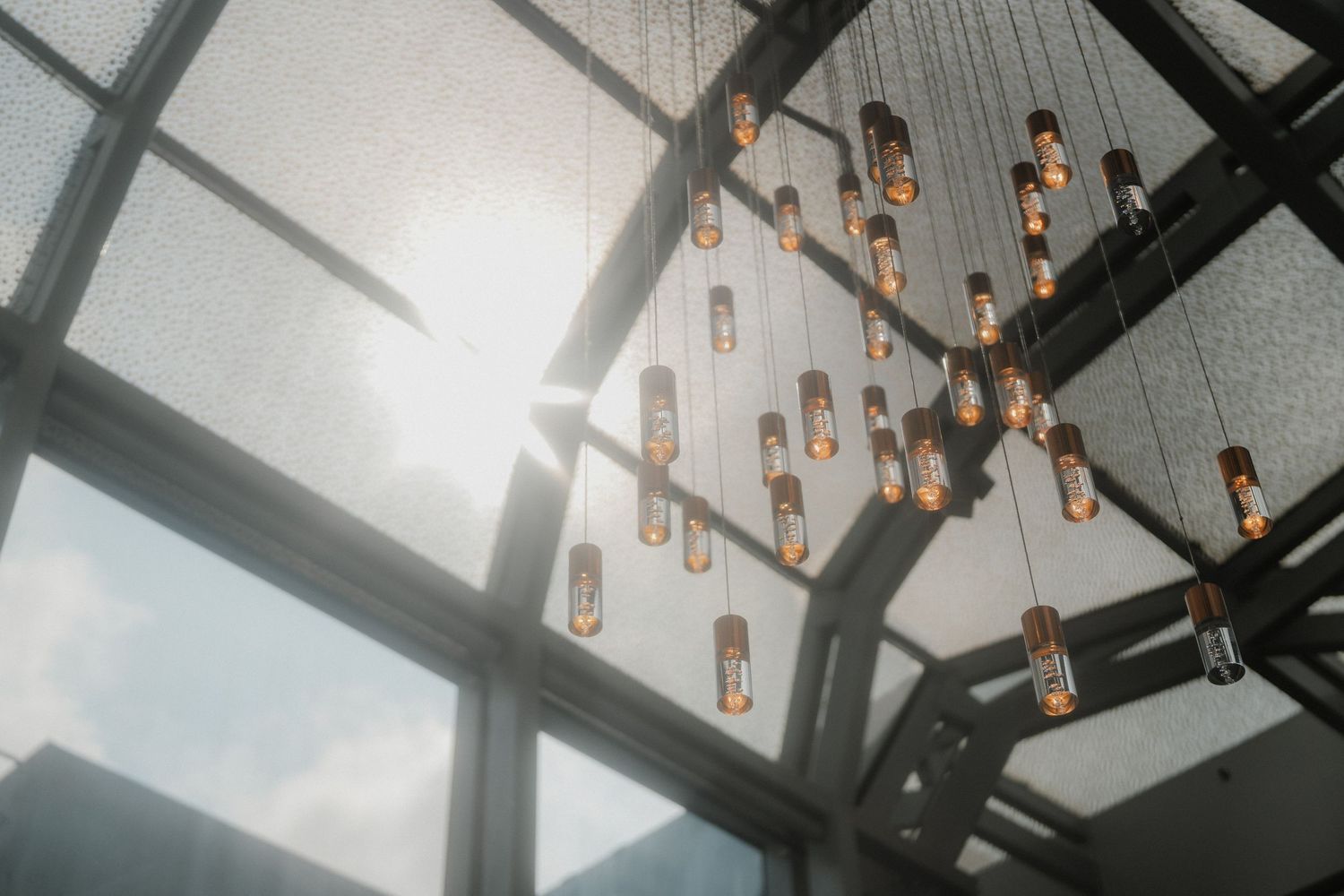 Hanging light fixtures and glass ceiling create an ethereal atmosphere in a wedding venue.