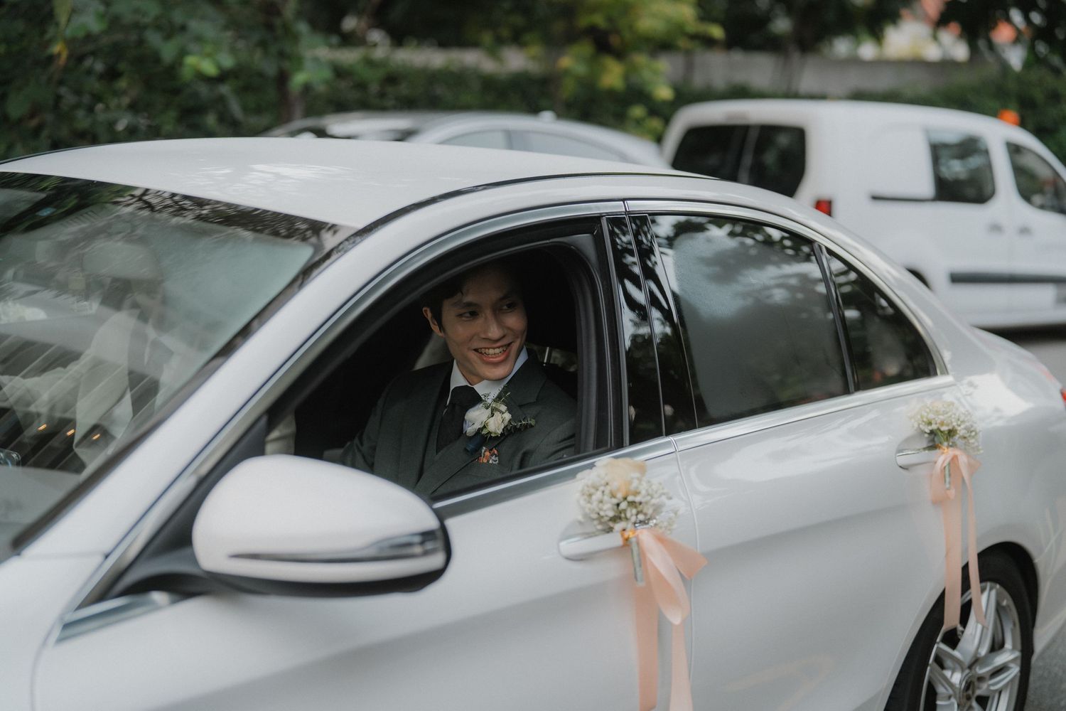 Row of decorated wedding cars with peach ribbons and floral arrangements in a parking lot.