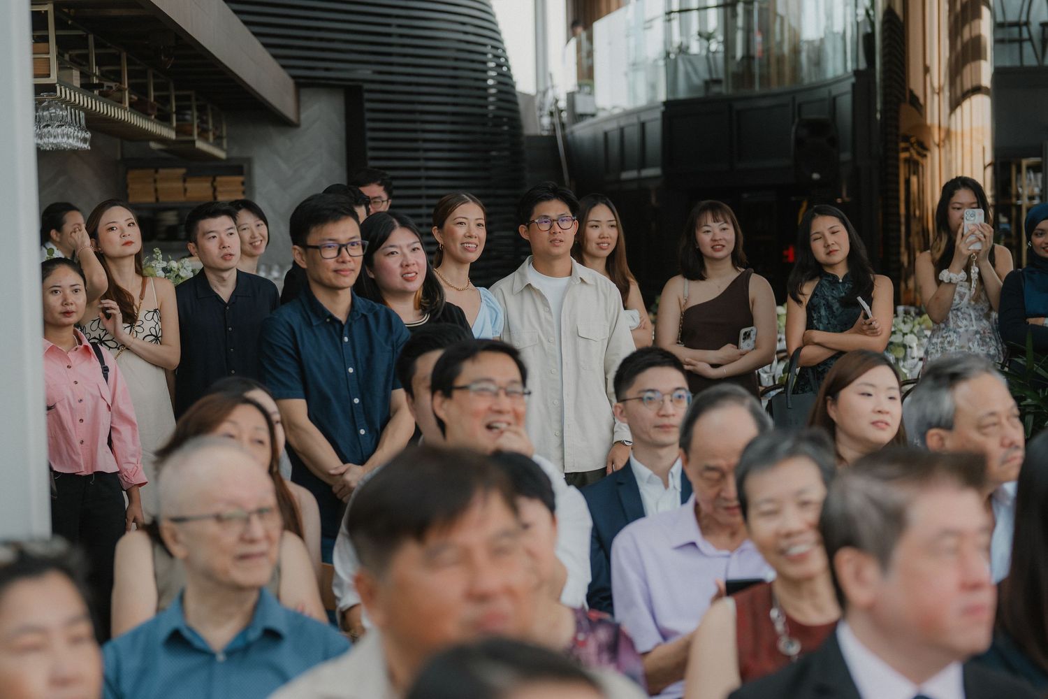 Wedding guests seated in rows during indoor ceremony watching attentively.