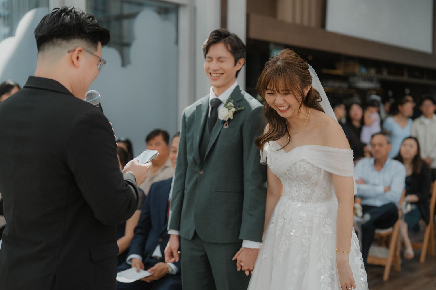 Wedding guests enjoy a joyful moment during an indoor ceremony with modern decor and natural lighting.