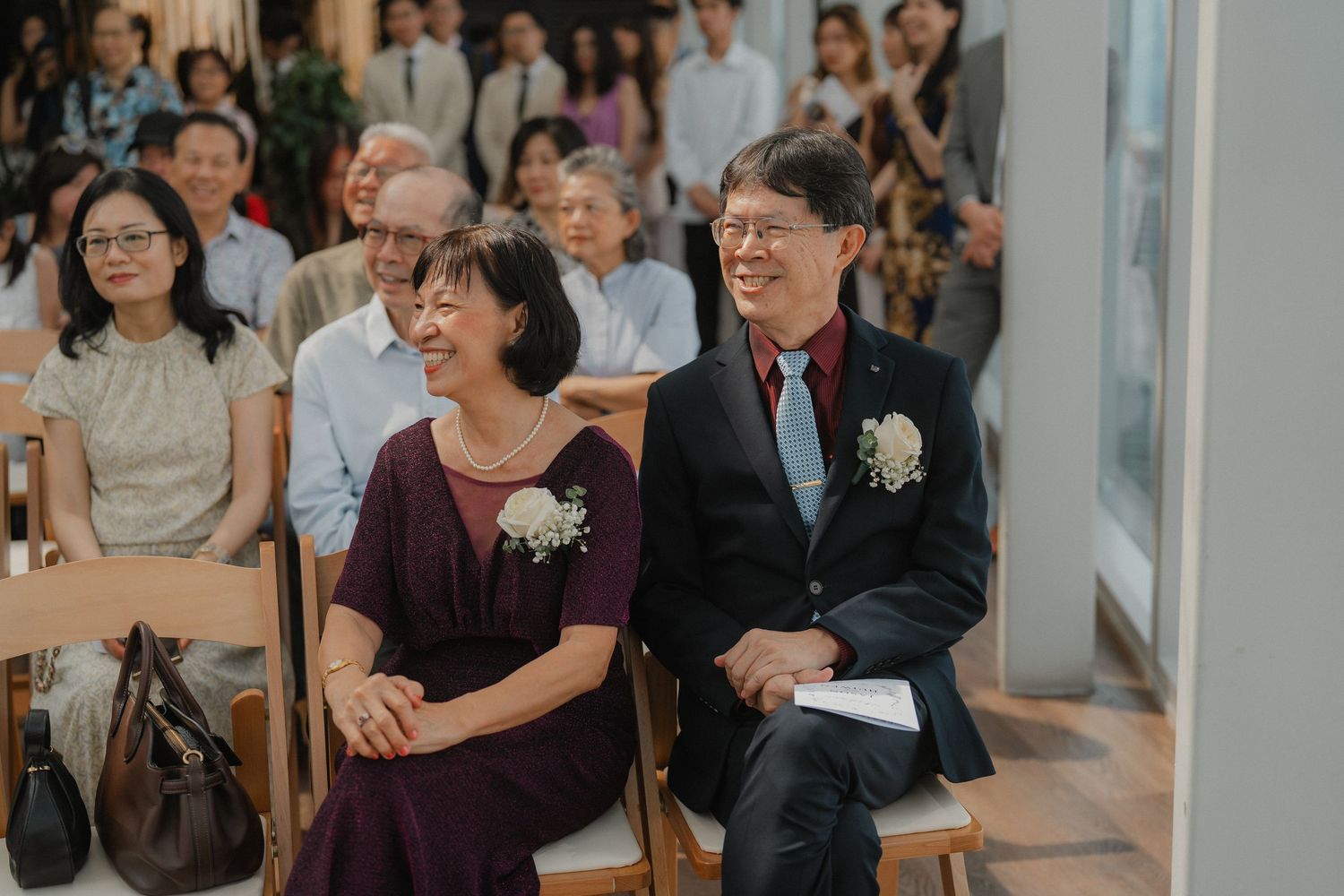 Wedding guests seated in rows watching the ceremony in a bright indoor venue.