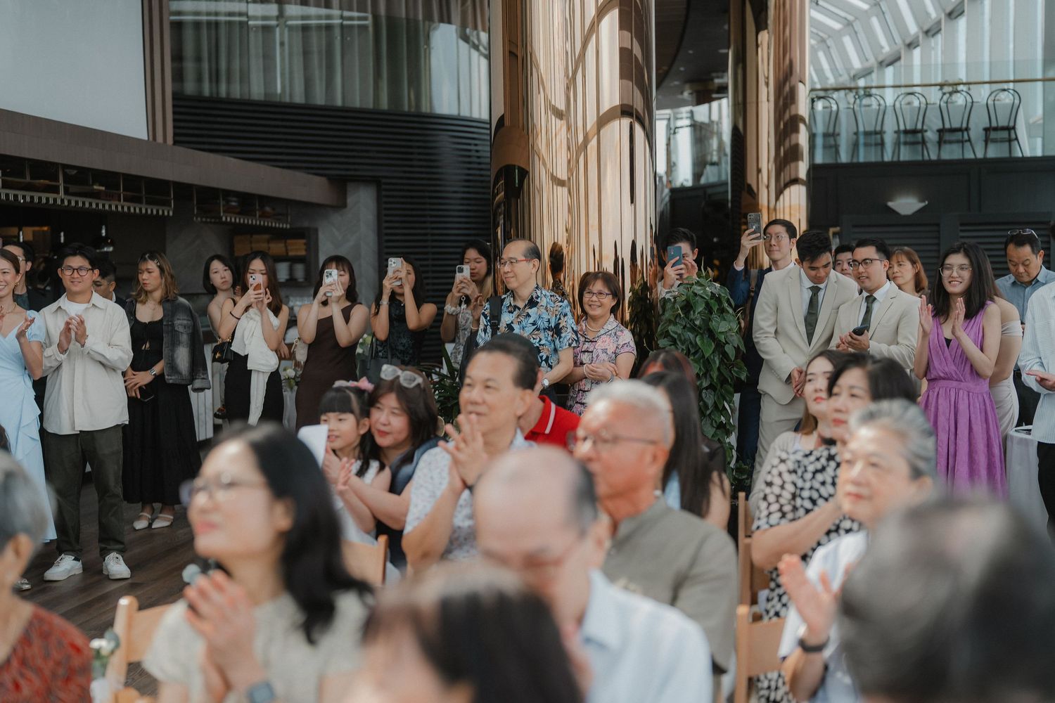 Wedding guests standing and applauding during celebration in an indoor venue.