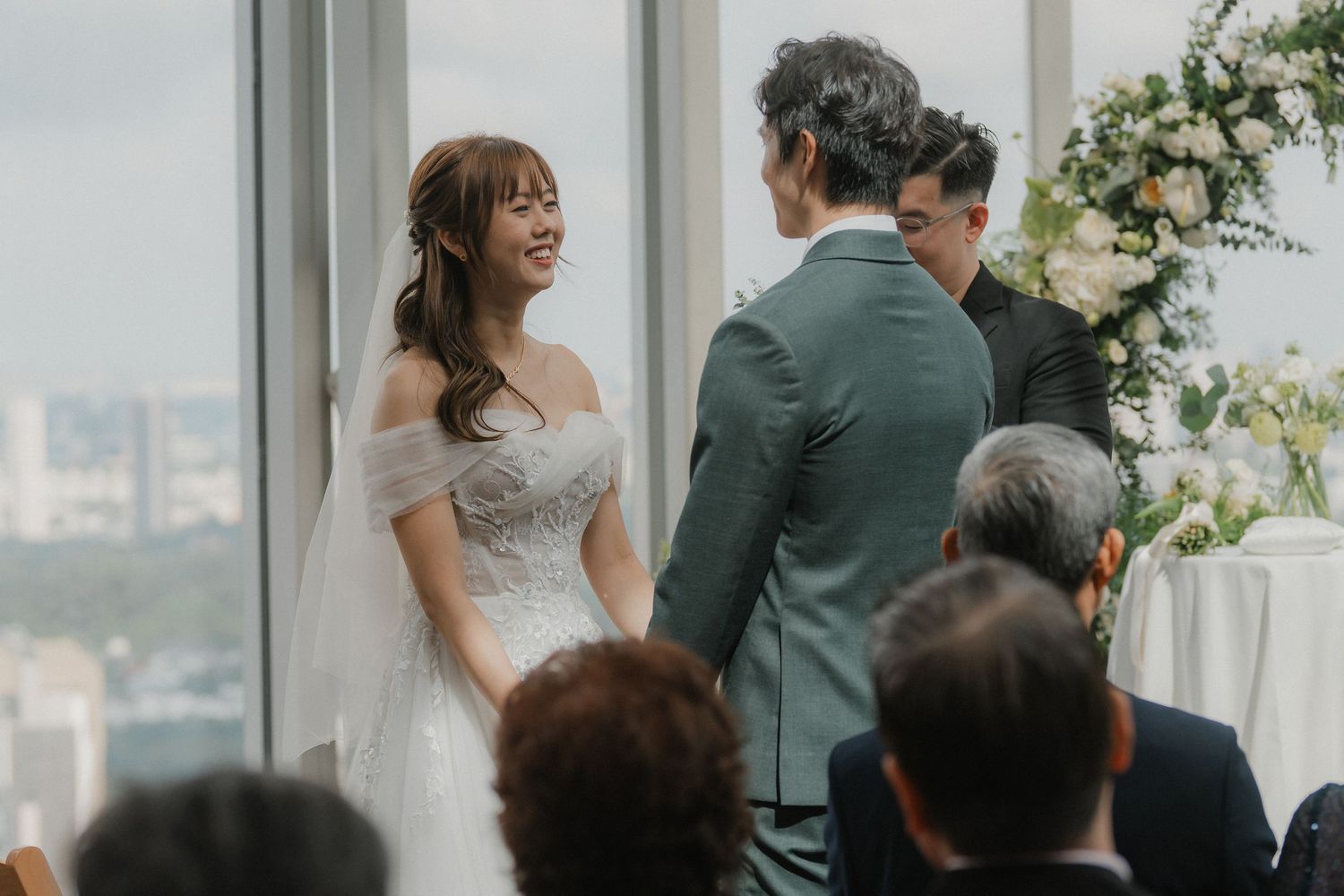 Intimate wedding ceremony moment in a light-filled modern venue with panoramic windows.