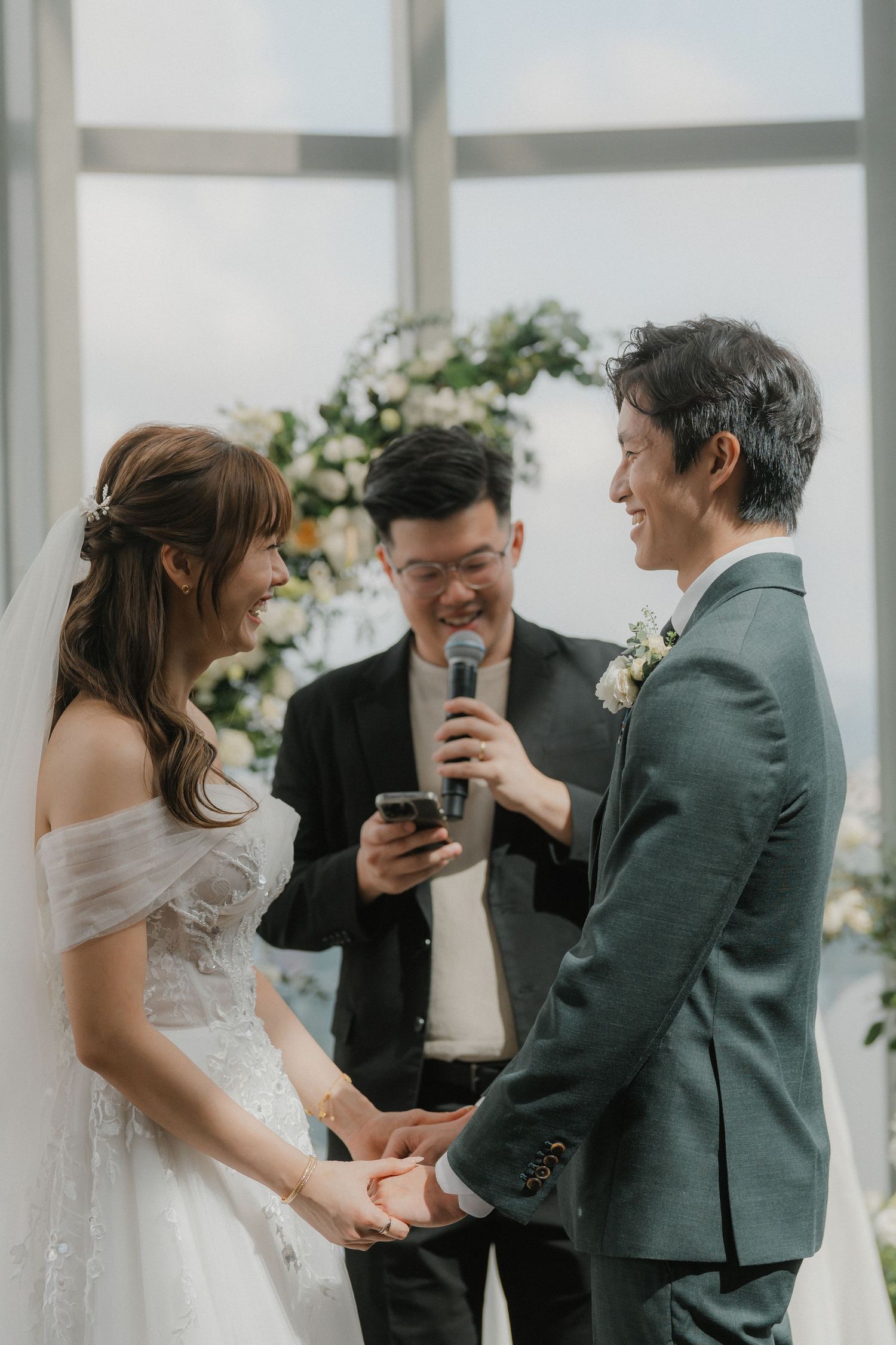 Intimate wedding ceremony with guests gathered around a light-filled modern space with floor-to-ceiling windows.