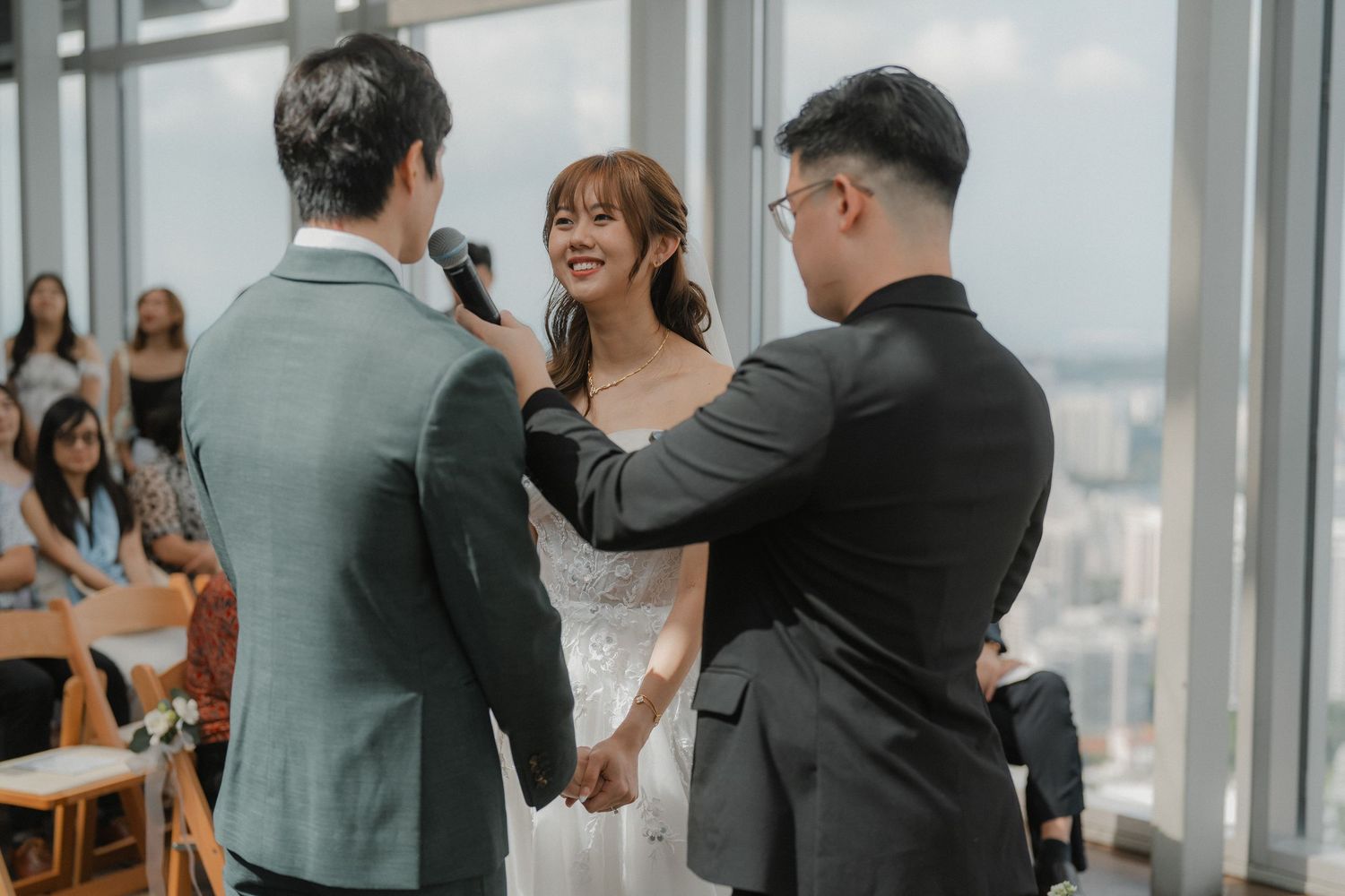Wedding ceremony moment in modern venue with large windows.