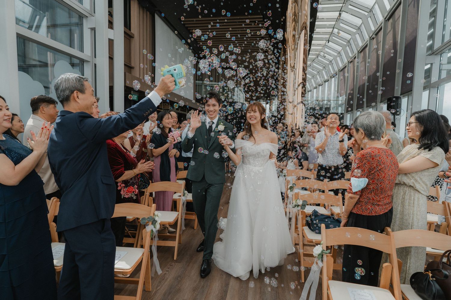 Joyful wedding celebration with guests throwing confetti in an indoor venue.