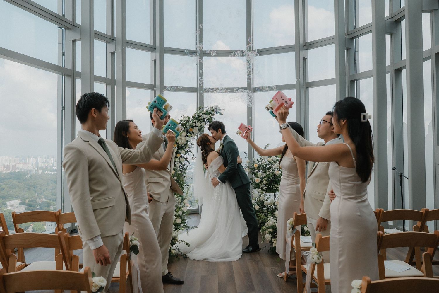 Wedding celebration in a sunlit glass venue with celebratory decorations and natural light.