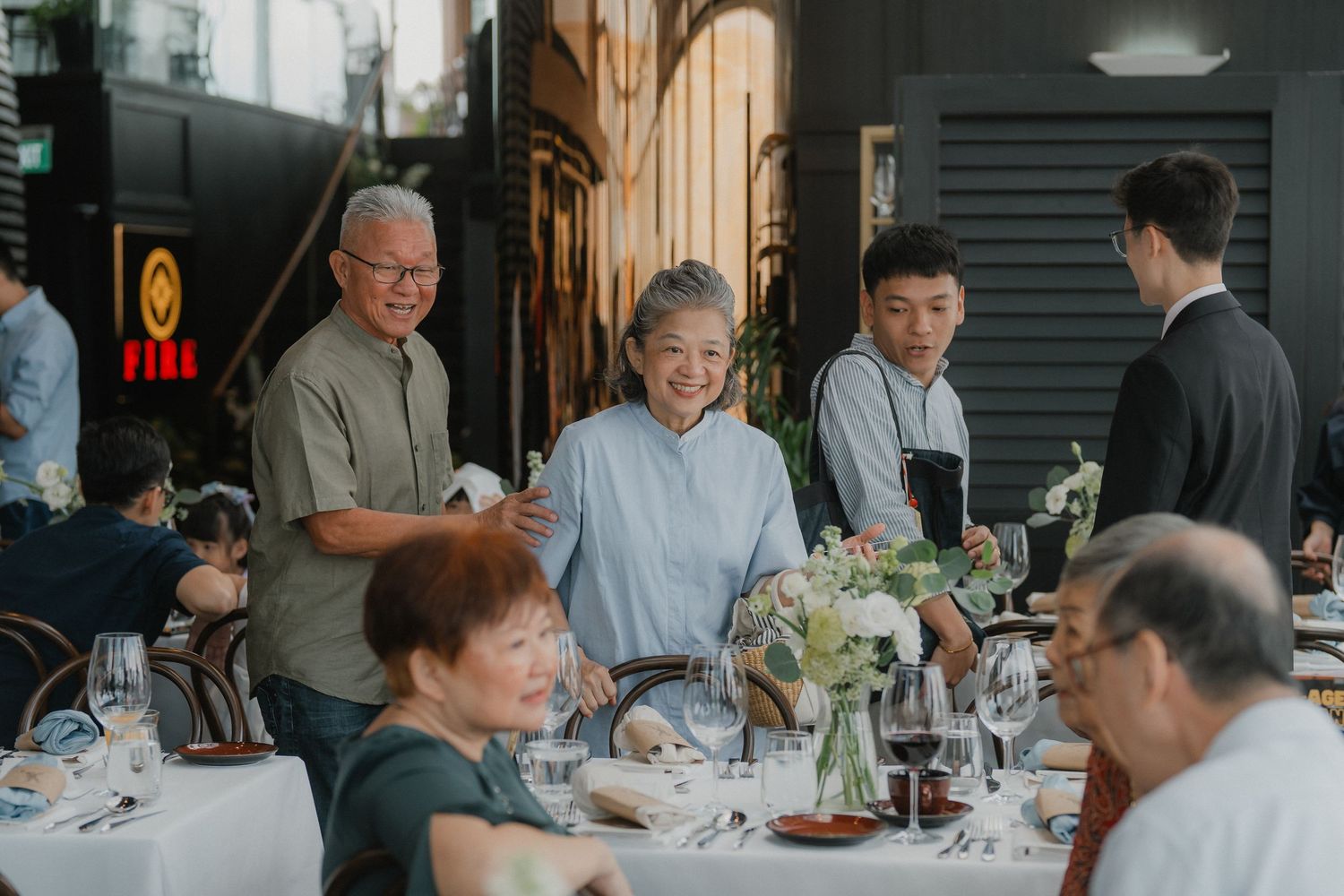 Wedding guests enjoying a celebration dinner at round tables with elegant place settings.