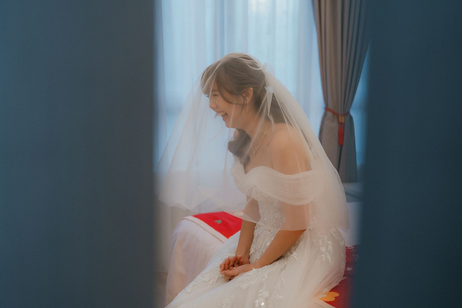 Wedding veil floating delicately against a dark blue background in an ethereal indoor setting.