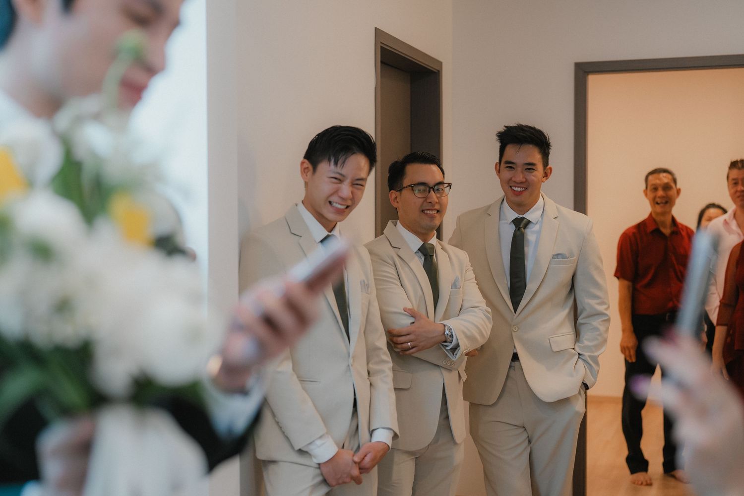 Wedding celebration with attendees in light gray and neutral formal attire at an indoor venue.