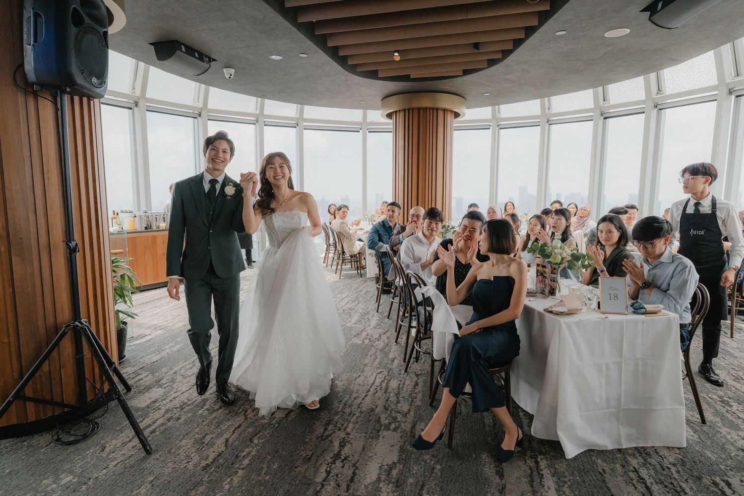 Wedding reception in a circular room with panoramic windows and guests seated at decorated tables.
