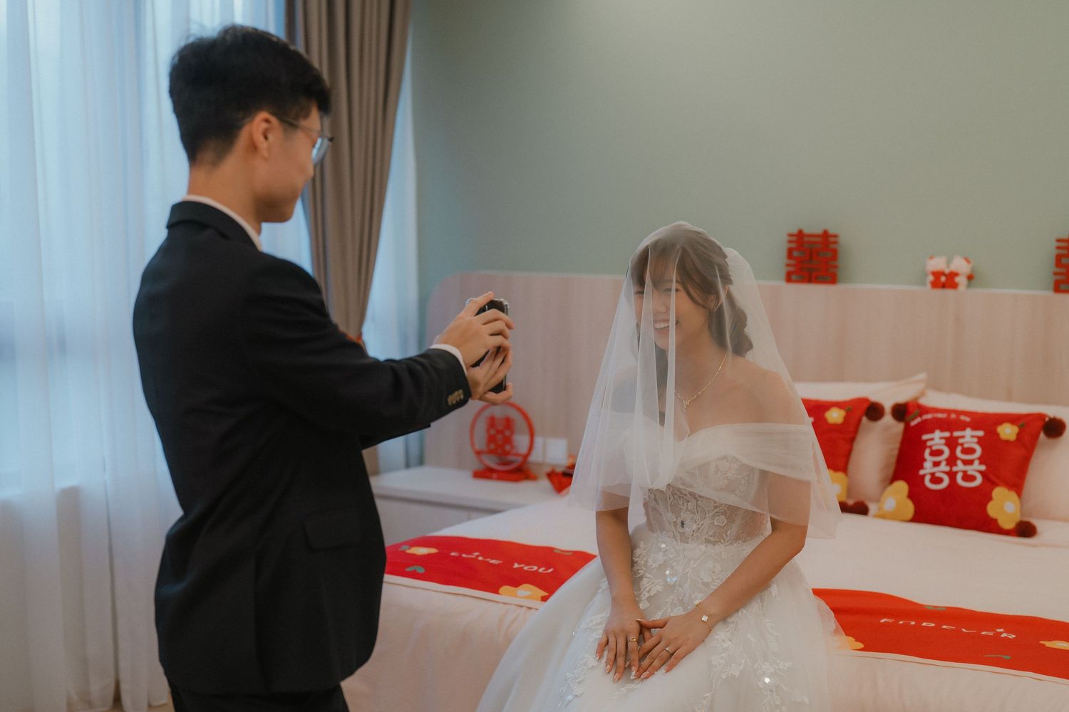 Modern wedding venue setup with white and red decor elements and curtained windows.