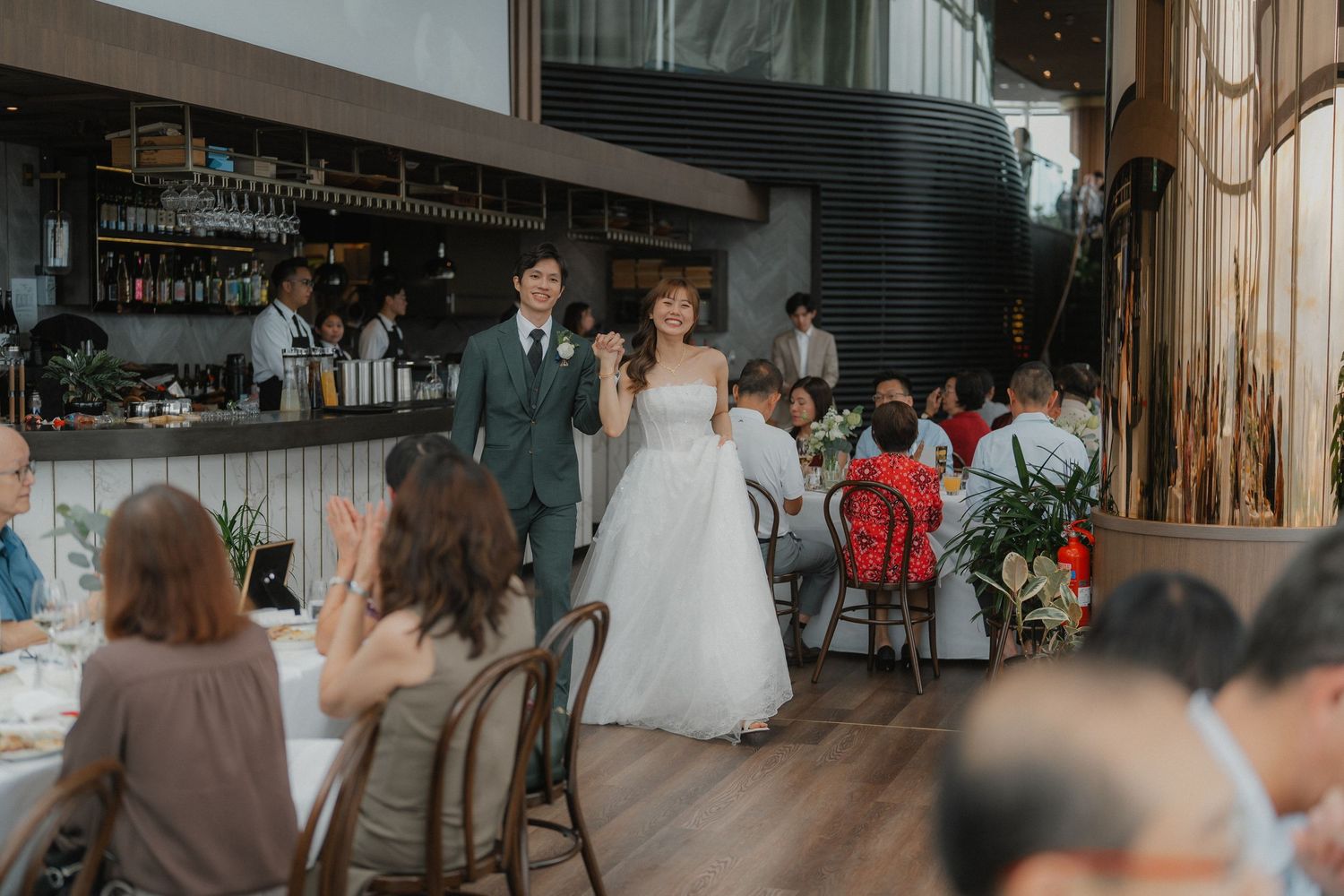 Wedding reception in modern restaurant venue with bar and dining setup.