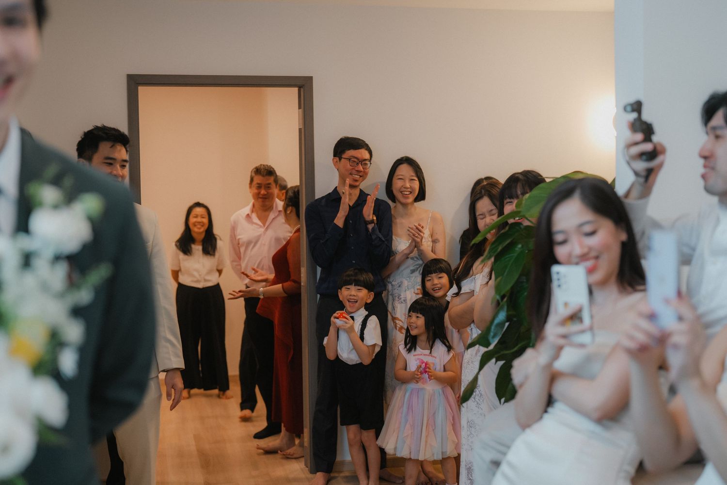 Wedding guests line up along a hallway wall for group photos.