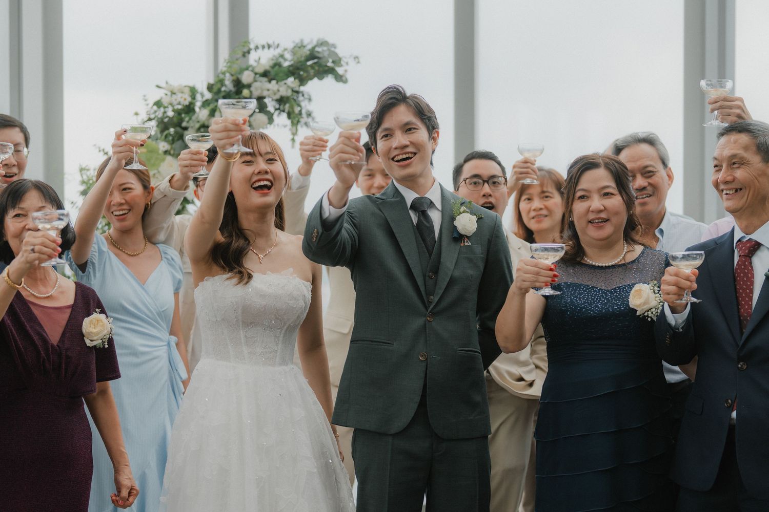 Wedding guests raise champagne glasses for a celebratory toast in a modern venue.