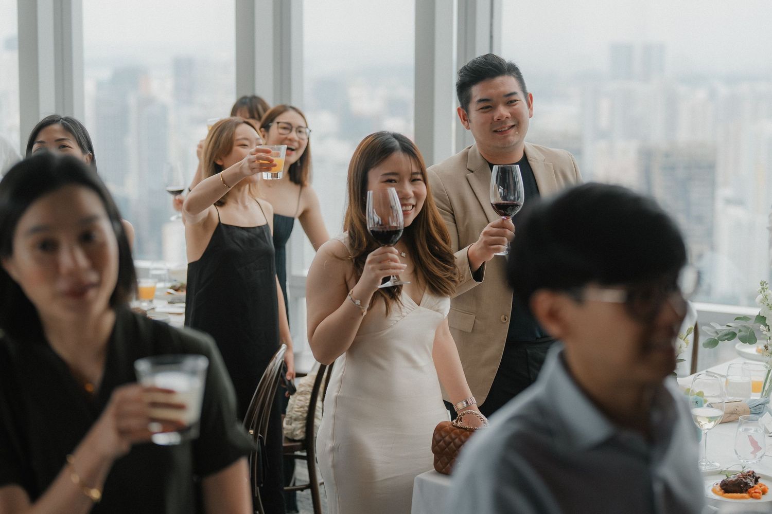 Wedding guests enjoying drinks and celebrations in modern high-rise venue with city views.