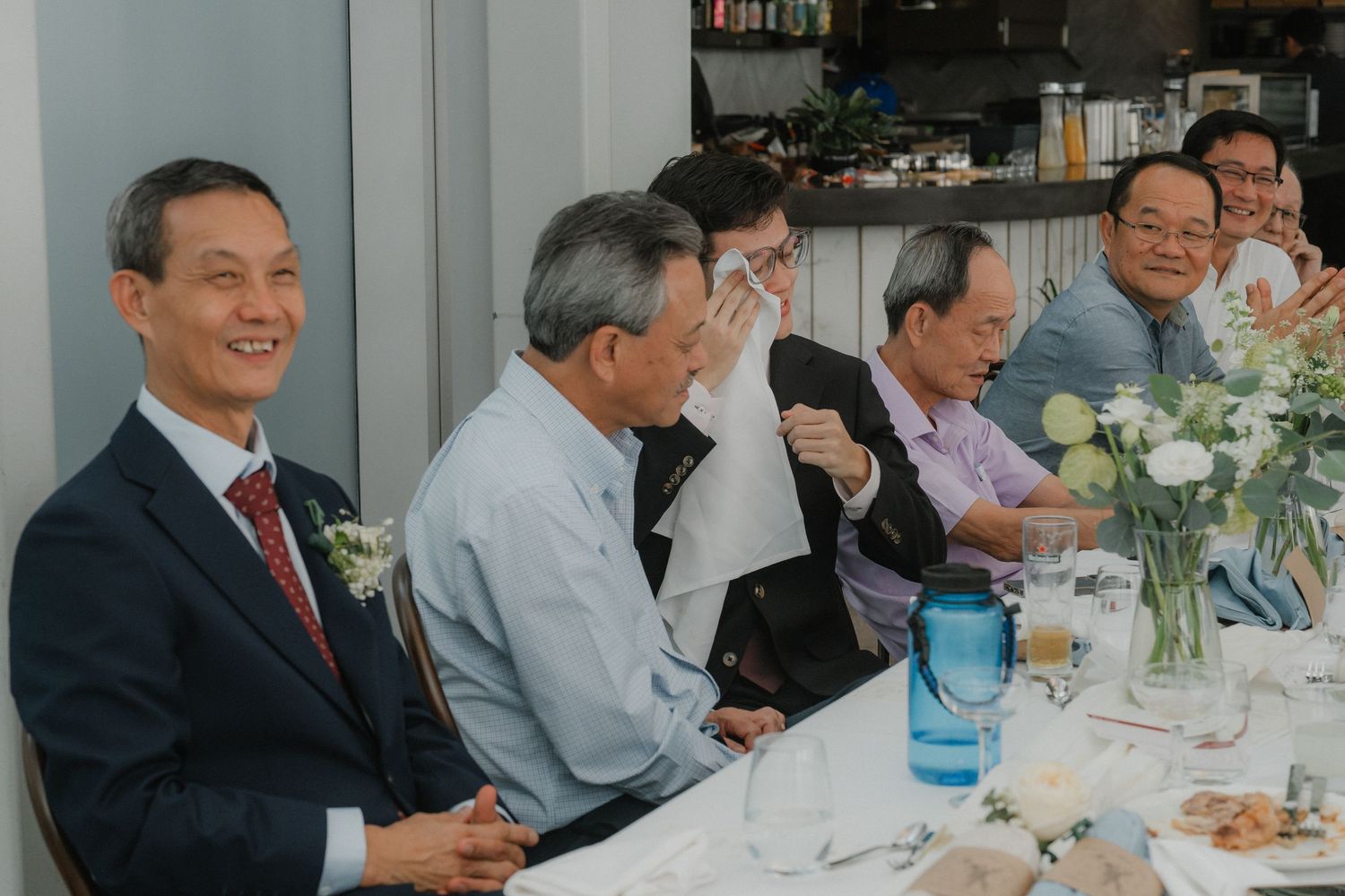 People gathered around a dining table at a formal event share conversation and laughter.
