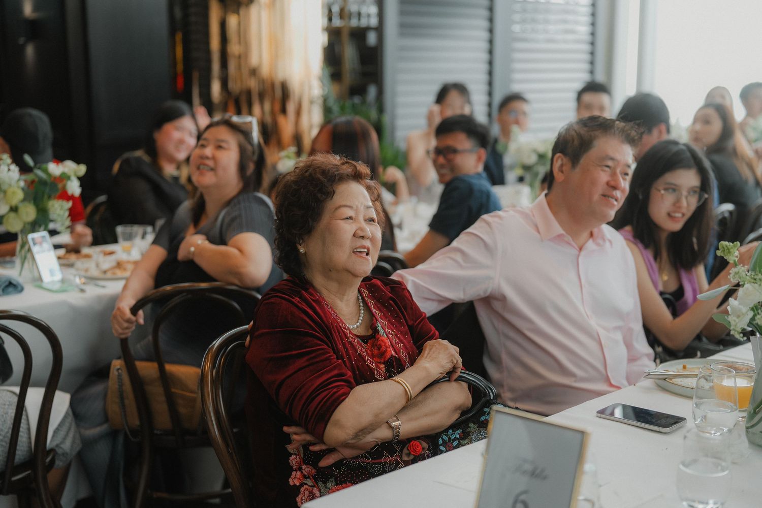 A group of guests share laughter and emotions during a celebration at a restaurant.