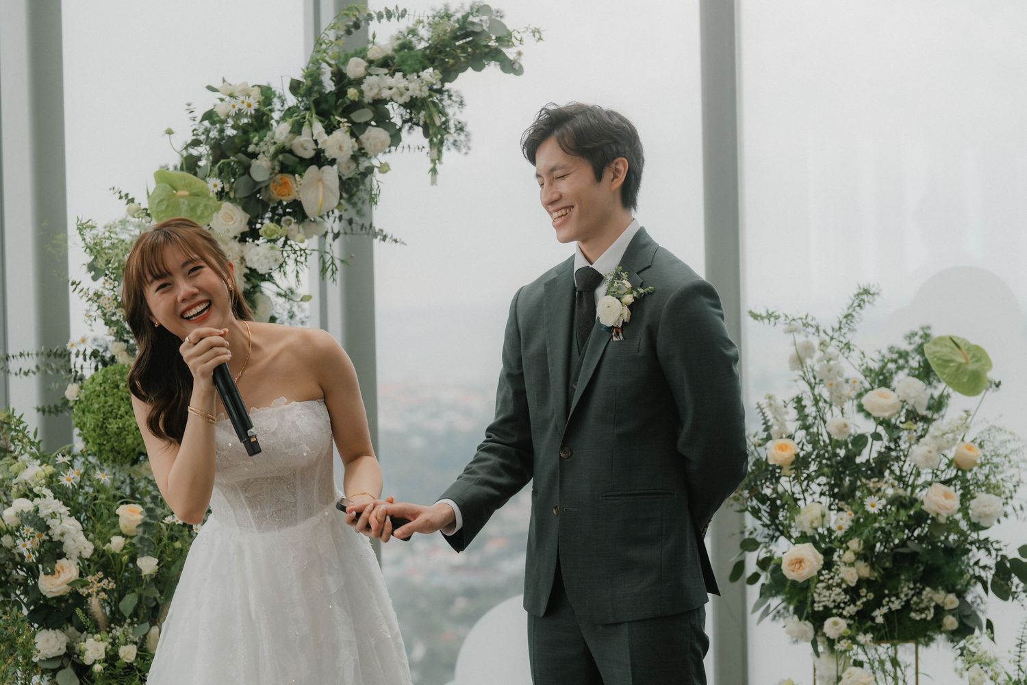 Newlyweds sharing joyful moment while creating champagne tower at modern wedding venue.