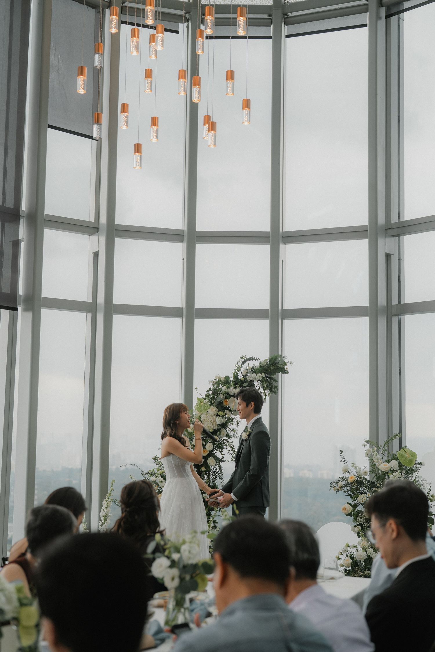 Elegant wedding reception in a modern venue with floor-to-ceiling windows overlooking a cityscape.
