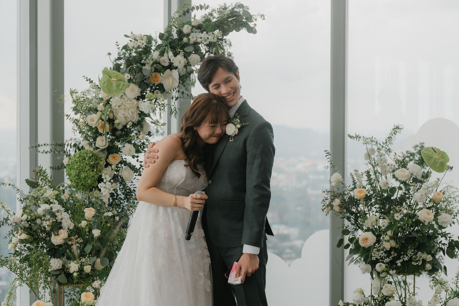 White floral arrangements and greenery decorating a modern wedding ceremony space.