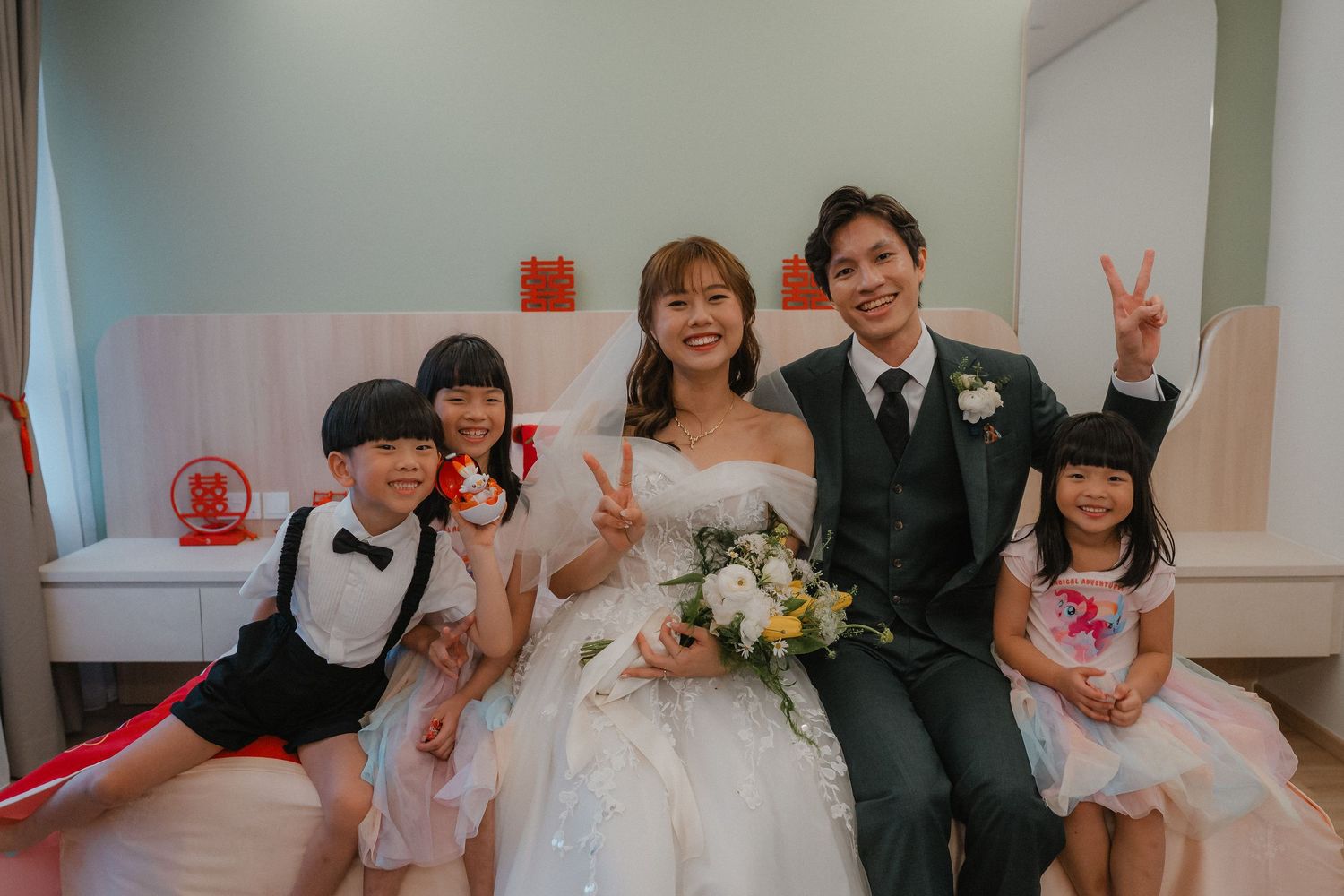 Wedding party gathered in bright indoor space with celebratory poses and formal attire.