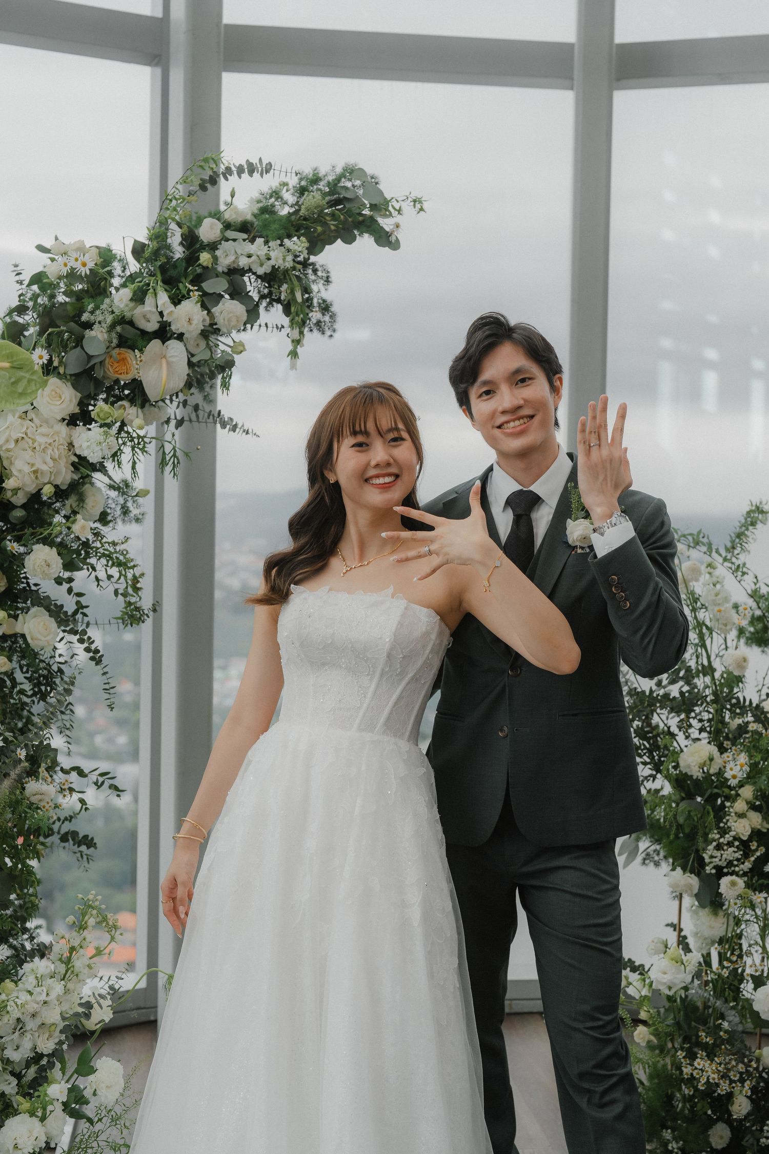 Wedding celebration in a light-filled venue decorated with white flowers and greenery.