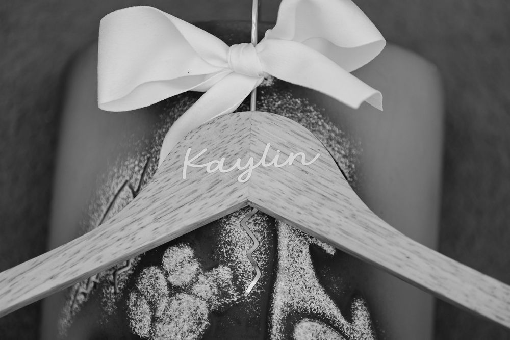 A white wooden wedding hanger with a bow and delicate lace details, captured in black and white photography.