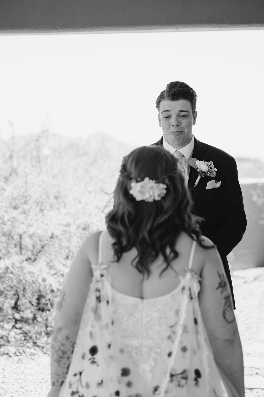 Black and white wedding photograph showing a sweet candid moment between newlyweds outdoors.