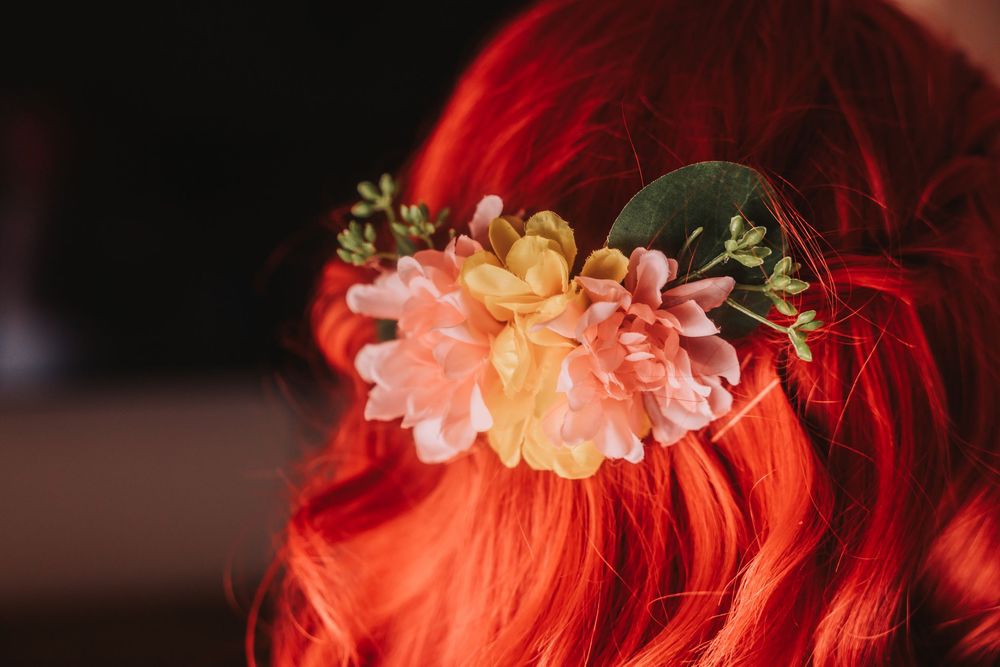 Red and pink flowers arranged in a beautiful floral arch with warm lighting against a dark background.