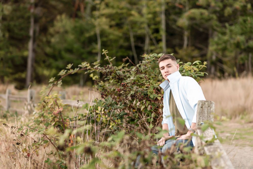 Wedding couple walks together joyfully through tall grass and wildflowers in a sun-drenched meadow.