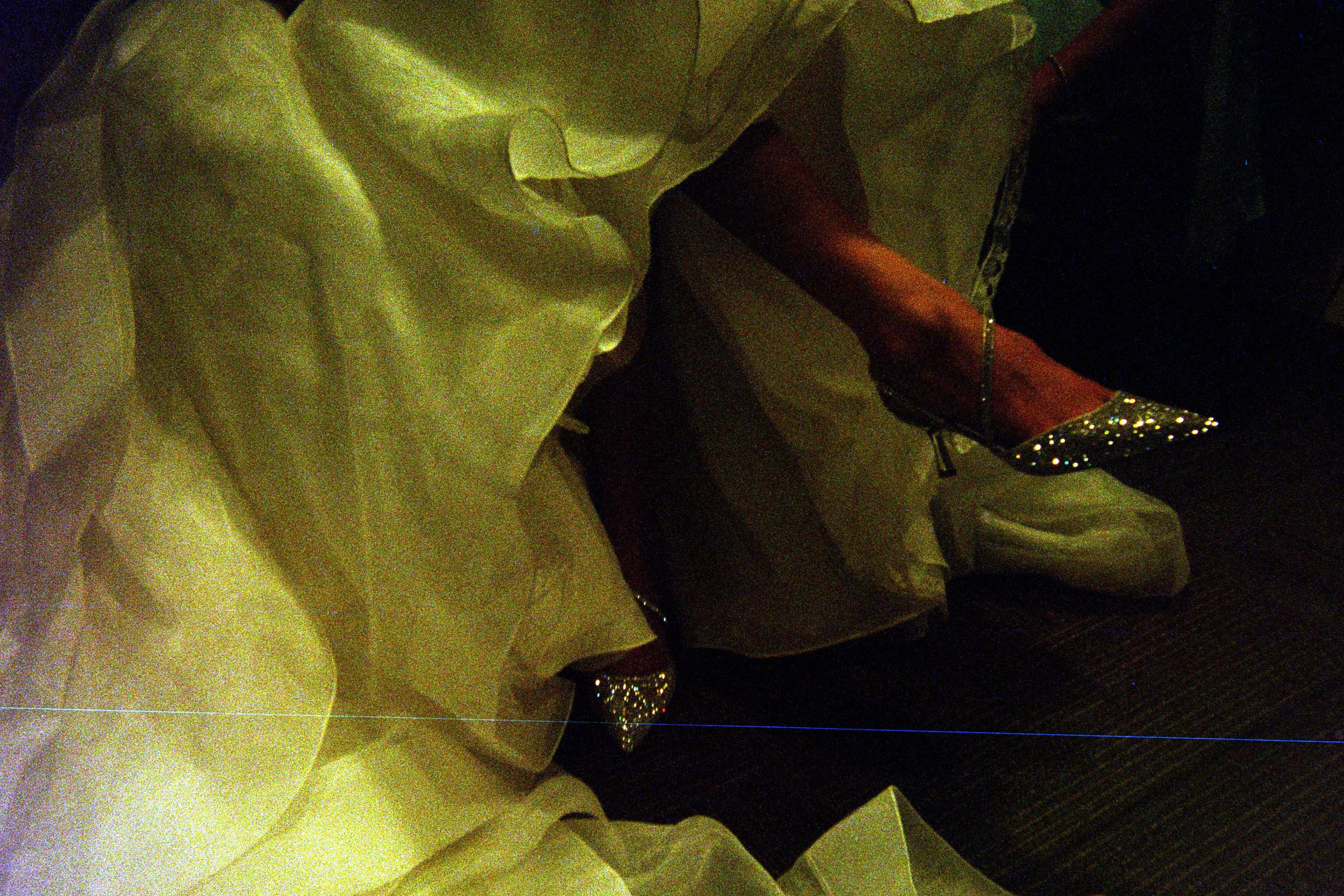 A fabric wedding dress train drapes elegantly down a dark wooden staircase.