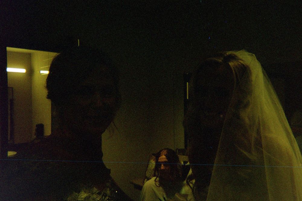 A wedding couple in formal attire sharing an intimate dance moment in a dimly lit reception venue.
