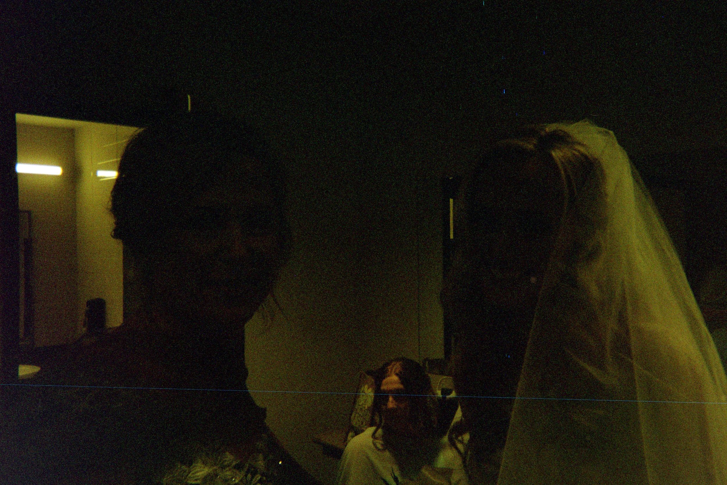 A wedding couple in formal attire sharing an intimate dance moment in a dimly lit reception venue.