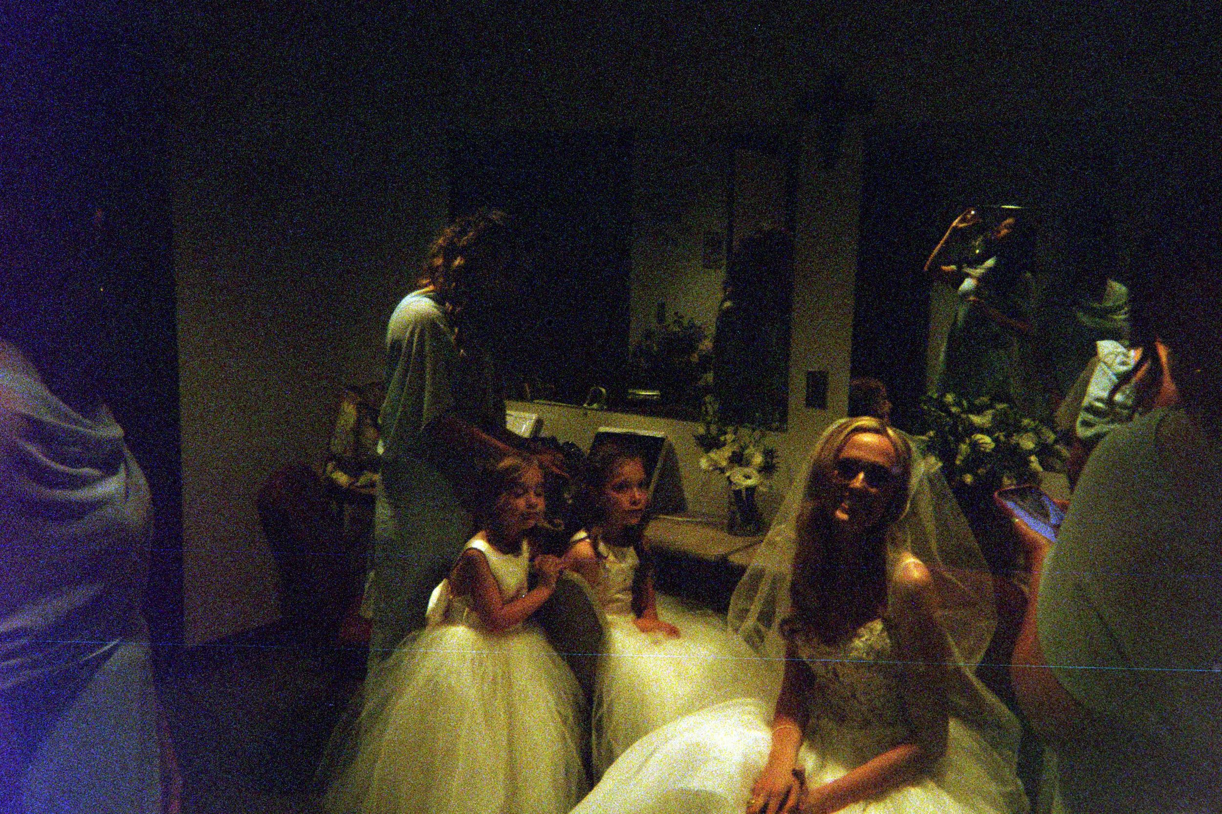 People gather in a dark room illuminated by spotlights during what appears to be a performance or event.