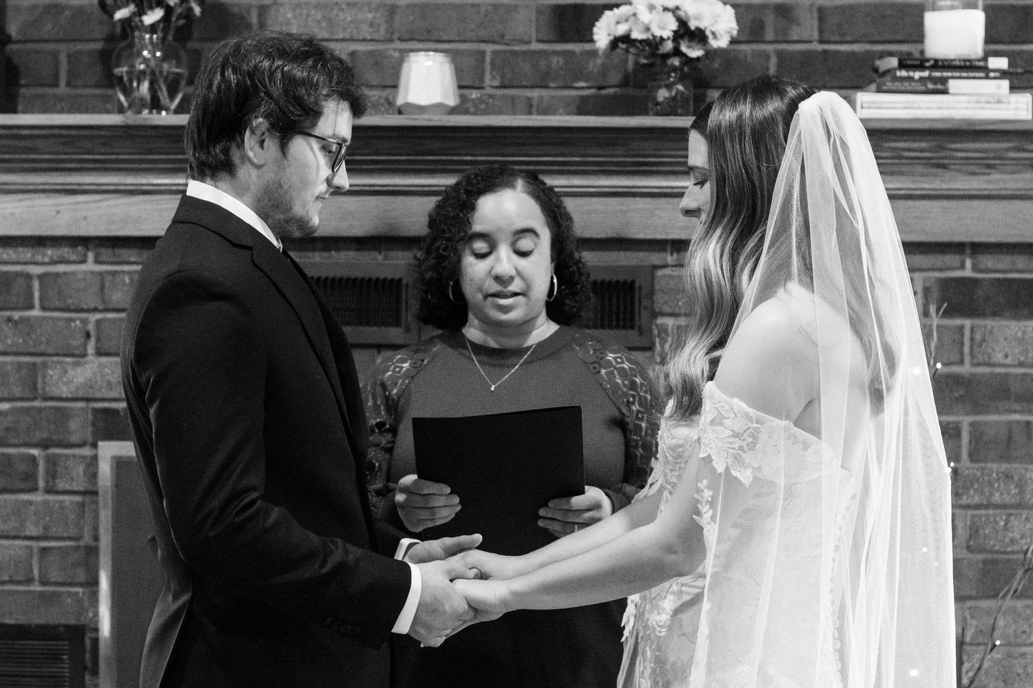 Bride and Groom hold hands as bride's sister officiates their wedding captured in Black and White