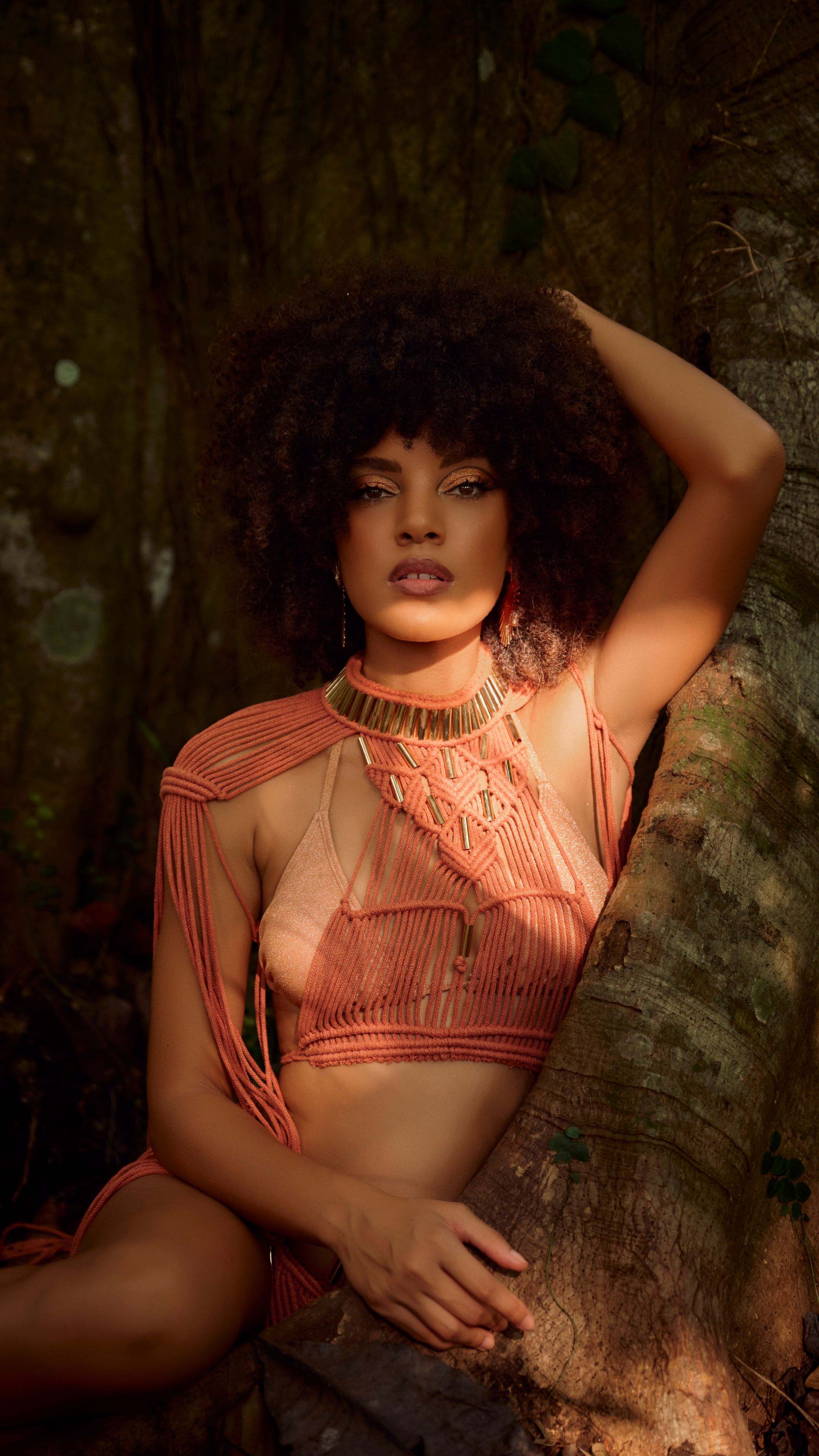Moody artistic portrait series with coral-colored clothing against a dark forest backdrop.