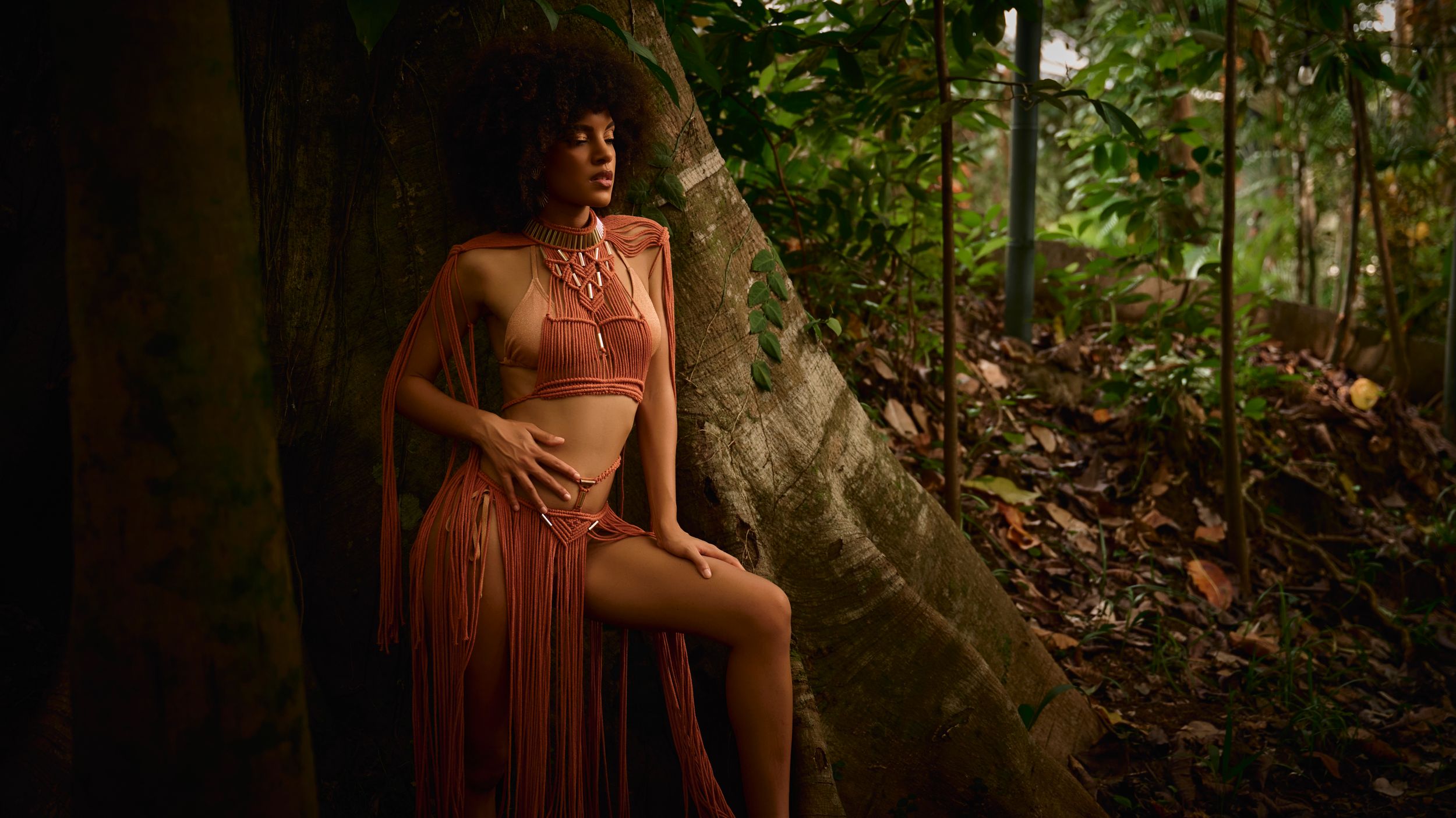 A series of artistic forest photos featuring a person in a flowing terracotta dress posing near trees and rocks in natural light.