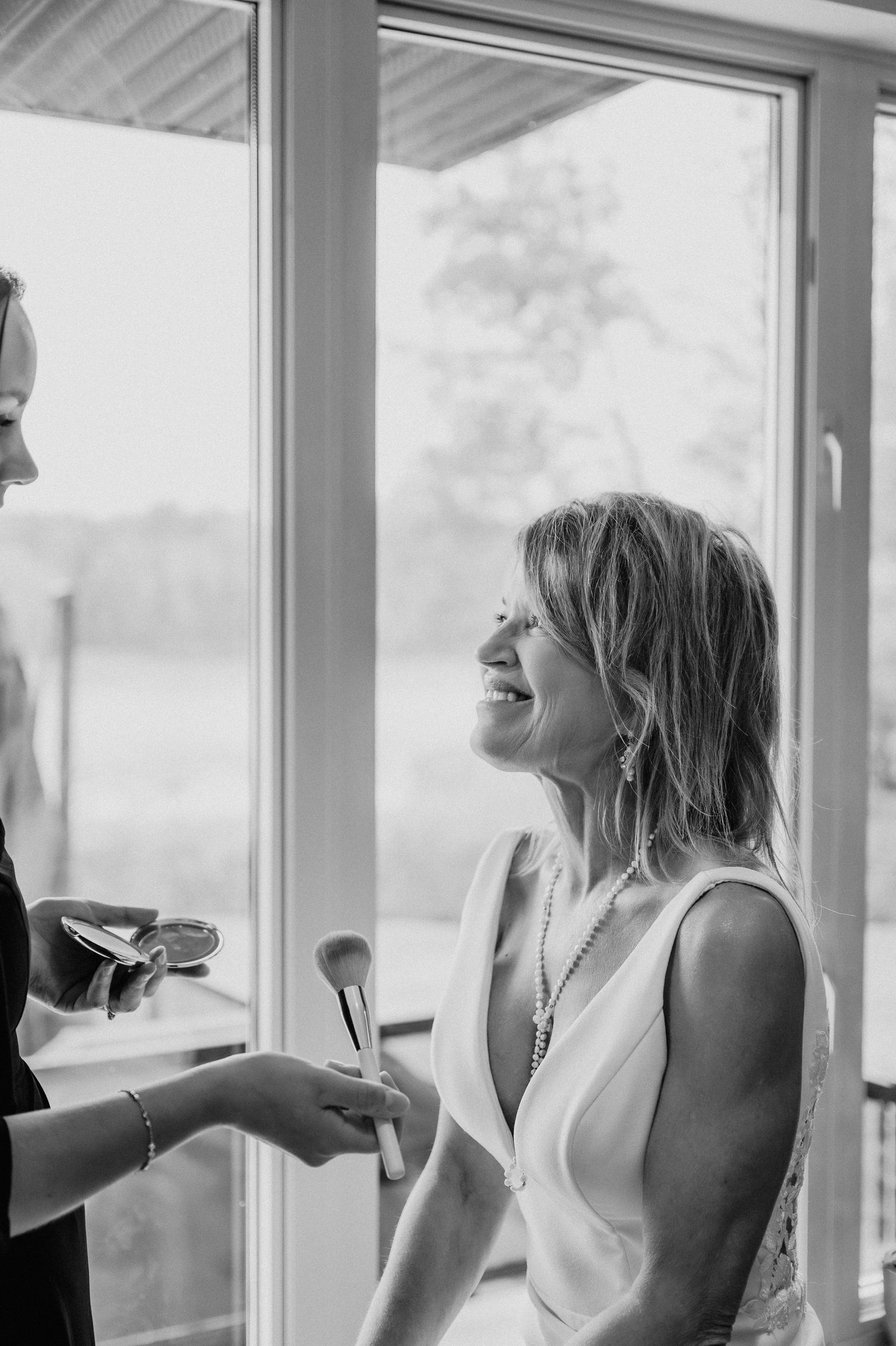 Candid getting-ready moment during wedding preparations by a window.
