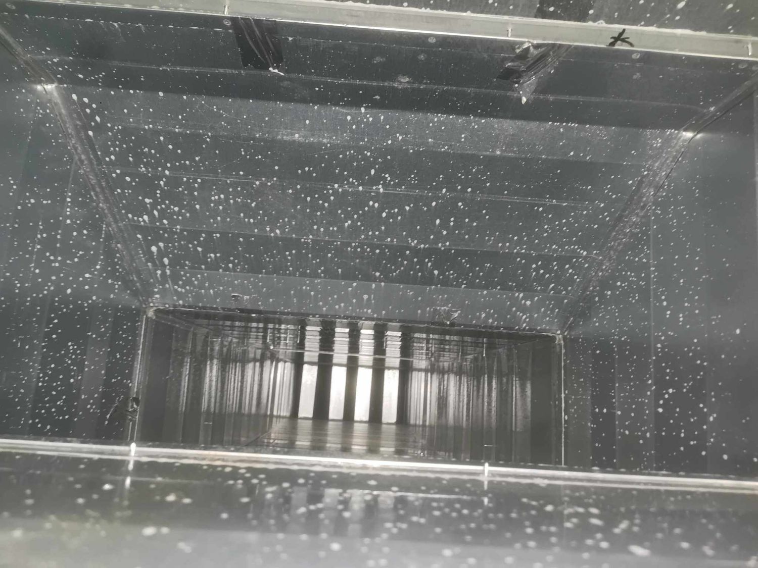 Water droplets visible on metal surfaces inside industrial ventilation ductwork.