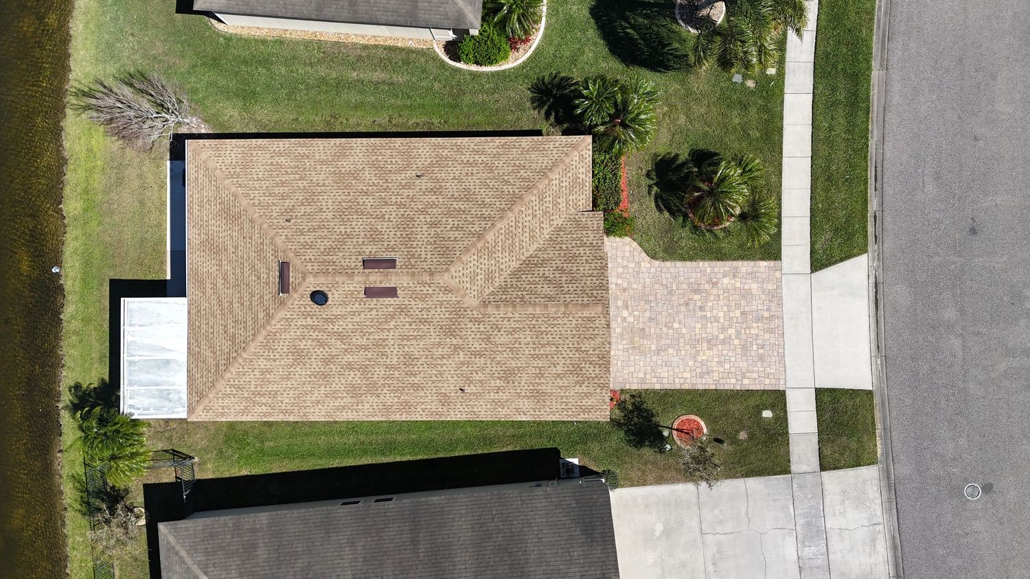 Aerial photograph of suburban homes with beige roofs and driveways along curved streets.