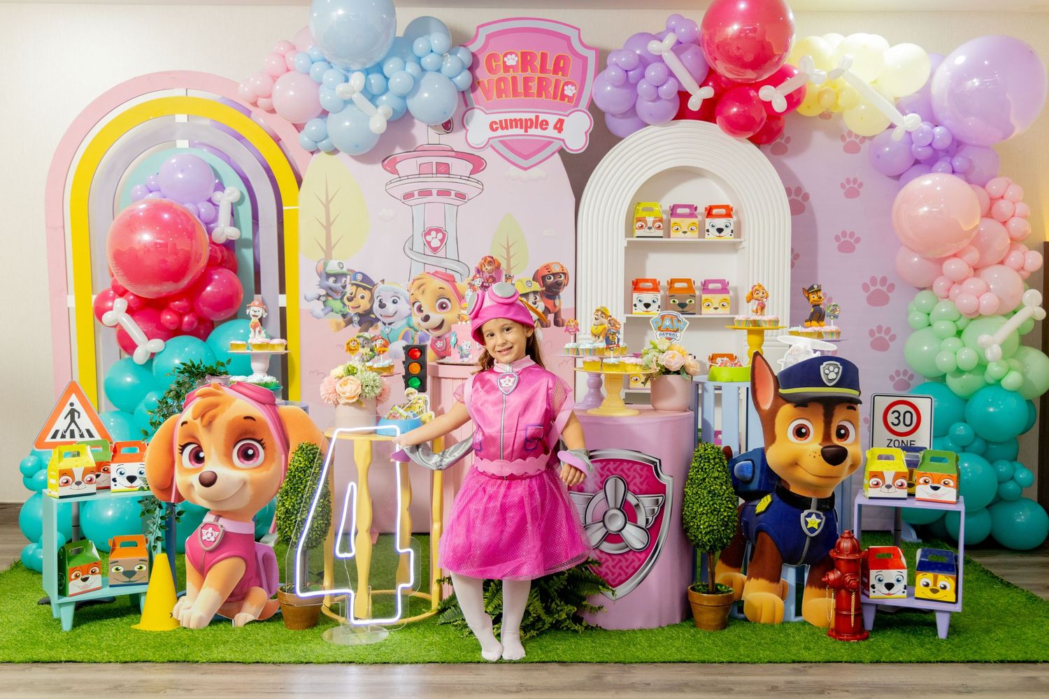 Colorful birthday party setup with Paw Patrol theme featuring balloon arch and decorative displays.