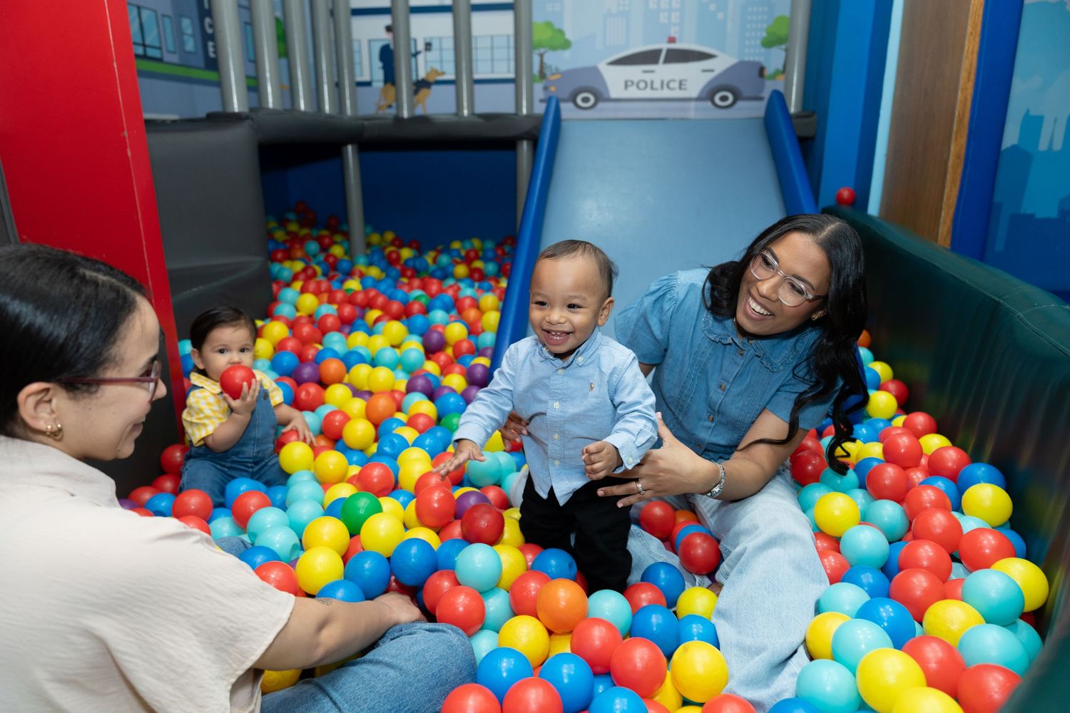 Children playing and having fun in a colorful ball pit at an indoor playground area.