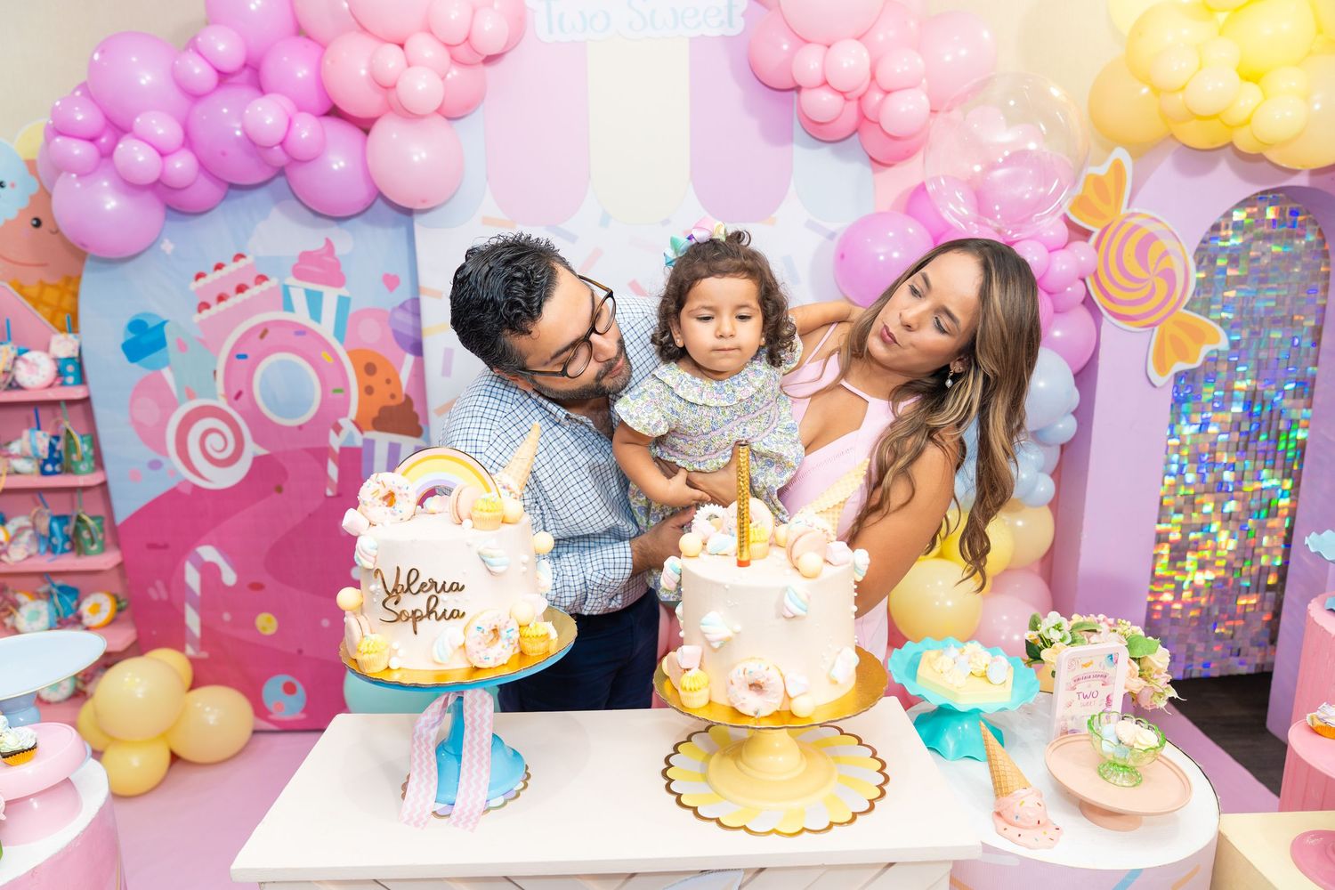 Colorful balloon arch and party decorations featuring pastel pinks, purples and yellows with festive birthday party elements.