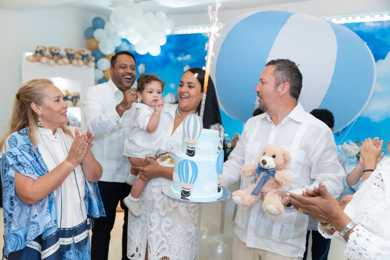 Group of people in white attire celebrating at a party with blue and white decorations.