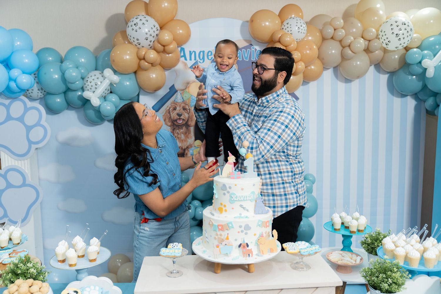 Gender reveal party celebration with blue and gold balloon decorations and dessert table setup.